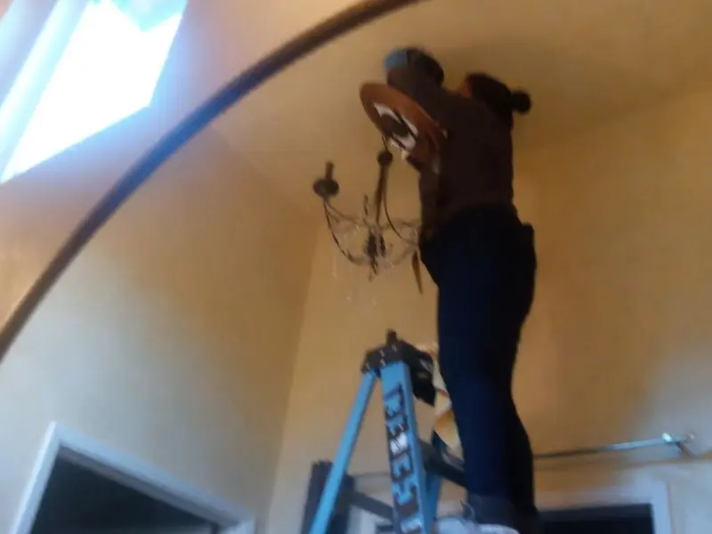 Electrician installing a chandelier in a Walker Mill residence